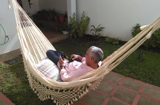 Persona descansando en un chinchorro de curagua en un jardín