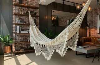 Chinchorro de curagua con malla calada y randas de macramé en un salón industrial