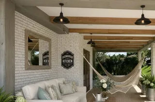 Chinchorro de curagua tradicional con malla calada abierta, cabuyeras y randas de macramé suspendido en un porche